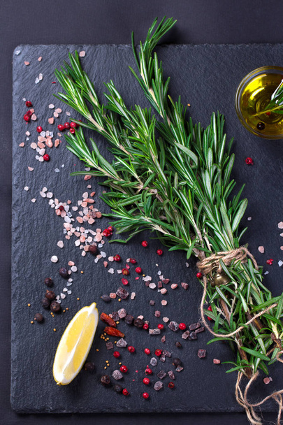 Rosemary plant, salt and spices on black slate board - Foto, Imagen