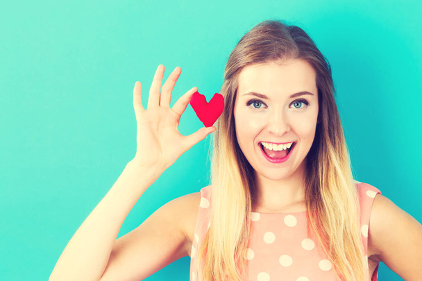 Happy young woman holding a heart cushion - Photo, Image
