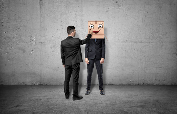 Businessman is drawing happy face on box which hides another mans head - Fotoğraf, Görsel