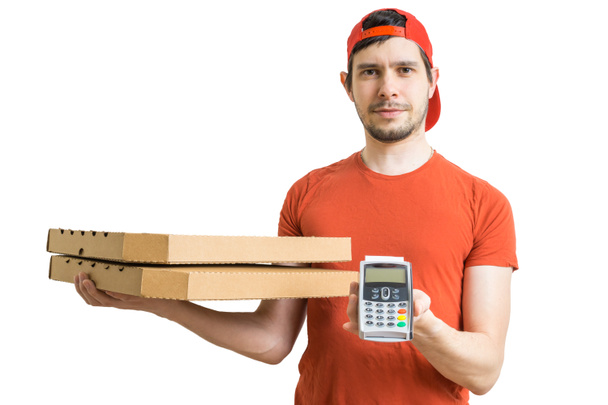 Young man is delivering pizza in boxes and holds payment terminal. Pizza delivery concept. Isolated on white background. - Foto, imagen
