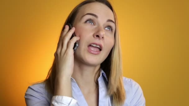 Beautiful young woman talking on mobile phone on yellow background. - Séquence, vidéo