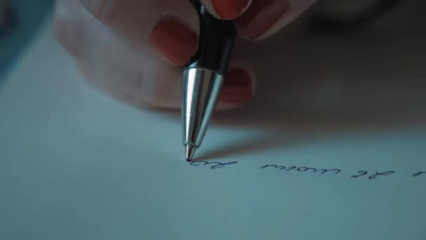 Közelről slowmotion női kéz vörös körömlakk írás tollal papírra - Felvétel, videó