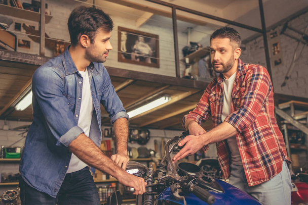 Faceci w sklepie naprawy motocykli - Zdjęcie, obraz