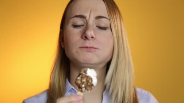 Young woman eating ice cream on a yellow background - Filmagem, Vídeo