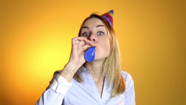 Girl inflating a balloon on a yellow background - Video