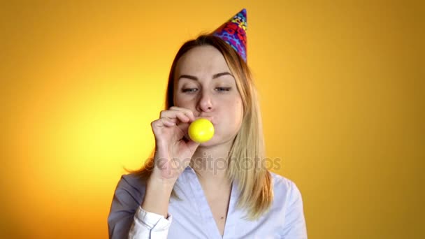 Beautiful girl blowing balloons on a yellow background - Imágenes, Vídeo