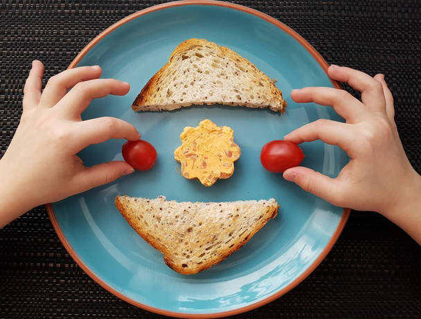 kinderhanden met toastjes, kerstomaten en kaas, bovenaanzicht  - Foto, afbeelding