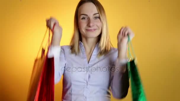 Shopping woman happy smiling holding shopping bags isolated on a yellow background. Lovely fresh young mixed race Asian Caucasian female model - Séquence, vidéo