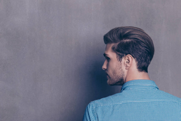 Back view of young modern brunet man on gray background - Zdjęcie, obraz