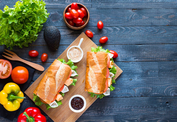 Вкусные и вкусные сэндвичи с индейкой, ветчиной, сыром, помидорами
 - Фото, изображение