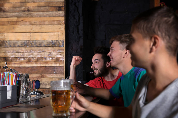 Cheerful friends with beer in sport bar - Фото, изображение