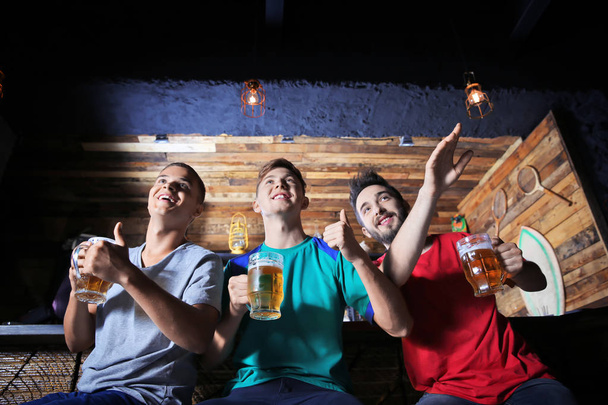 Cheerful friends with beer in sport bar - Foto, afbeelding