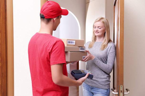 Young woman receiving package from courier - Foto, Bild