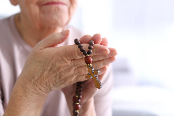 Elderly woman with rosary beads at home, closeup - Φωτογραφία, εικόνα