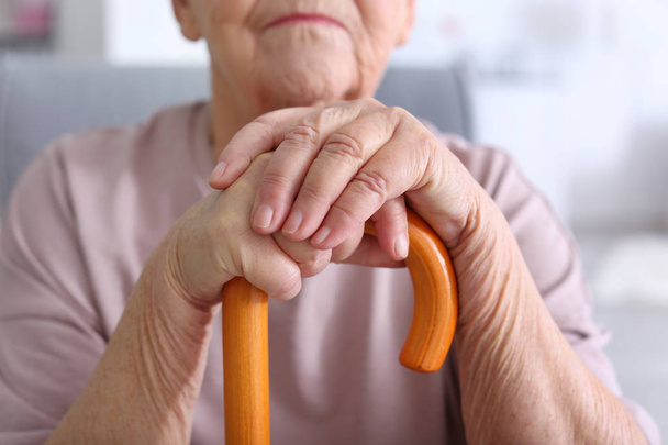 Elderly woman with walking stick at home, closeup - 写真・画像