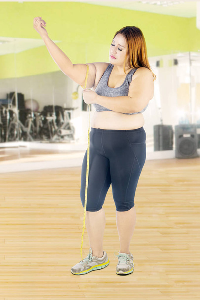 Woman measures her arm in fitness center  - Zdjęcie, obraz