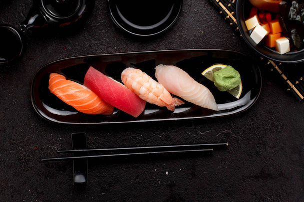Sushi set on a black plate and miso soup over dark concrete background - Zdjęcie, obraz
