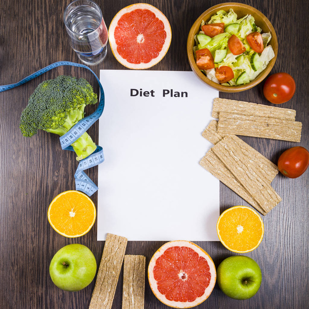 Food and sheet of paper with a diet plan on a dark wooden table. - Foto, immagini