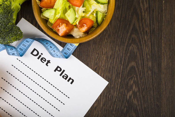 Food and sheet of paper with a diet plan on a dark wooden table. - Photo, Image