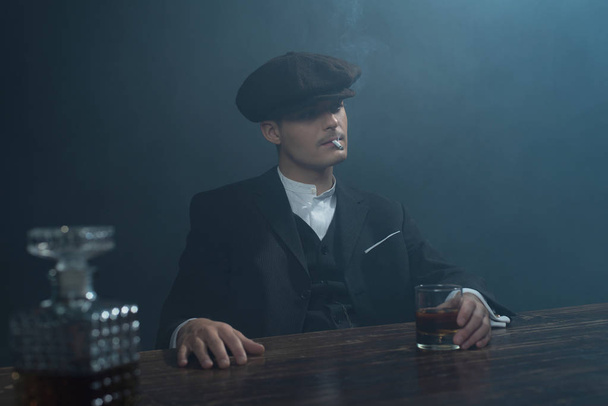 Gangster sitzt mit Whiskey am Tisch.    - Foto, Bild
