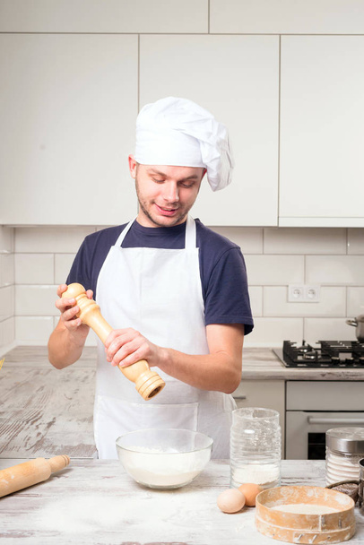 chef using pepper mill in kitchen - Foto, afbeelding