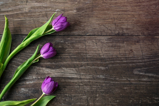 Purple tulips on wooden background top view - Valokuva, kuva