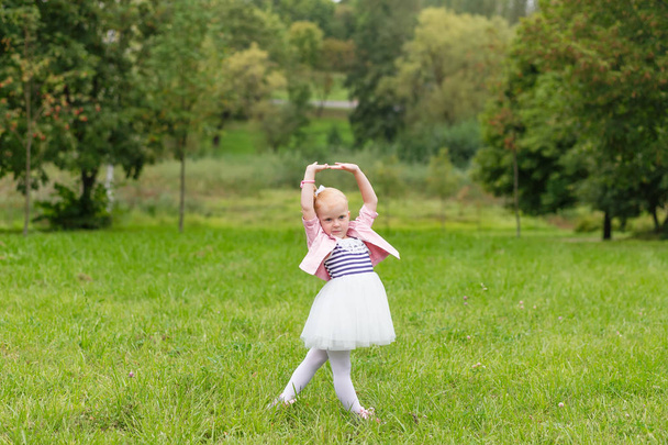 Sevimli küçük bir kız güzel bir elbise ve oynarken spor ayakkabı  - Fotoğraf, Görsel