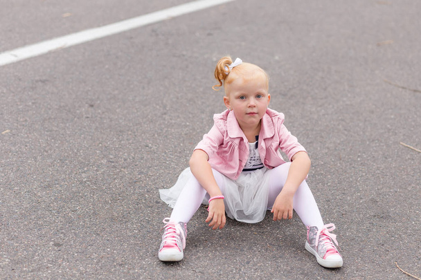 Симпатична маленька дівчинка в красивій сукні і кросівки грають на
  - Фото, зображення