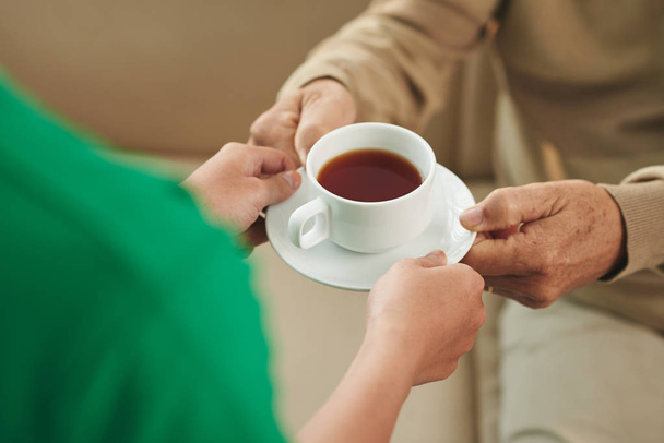 Enfermera dando taza de té al hombre
 - Foto, imagen