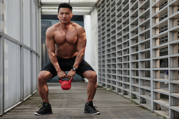 Sportsman doing squats with kettlebell - Photo, Image