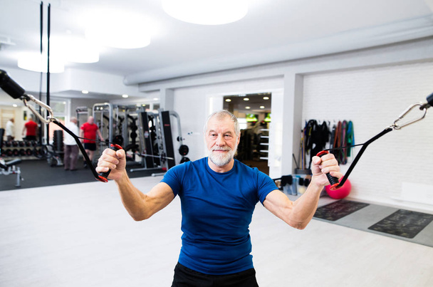 Fit senior man in gym working out with weights. - Valokuva, kuva