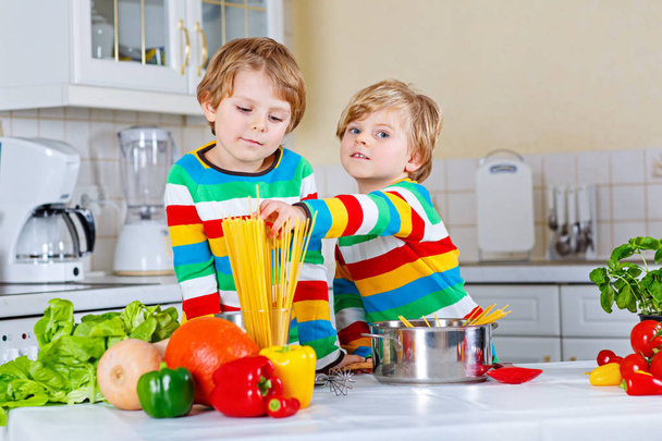 Kaksi pientä poikaa keittää pastaa vihannesten kanssa
 - Valokuva, kuva