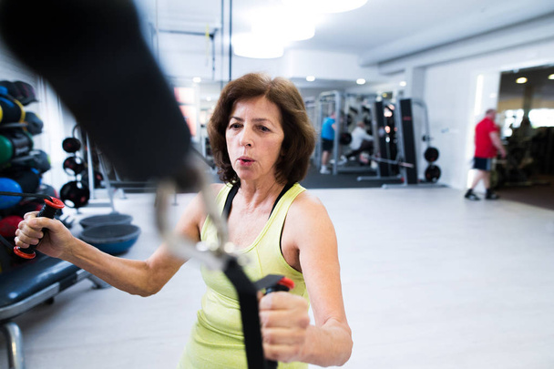 Senior woman in gym working out with weights. - Φωτογραφία, εικόνα
