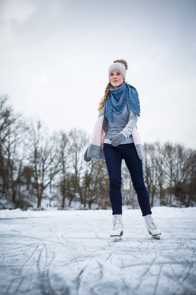 Young woman ice skating outdoors on a pond  - Φωτογραφία, εικόνα