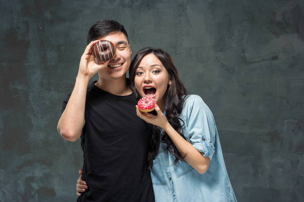 Young asian couple enjoy eating of sweet colorful donut - 写真・画像