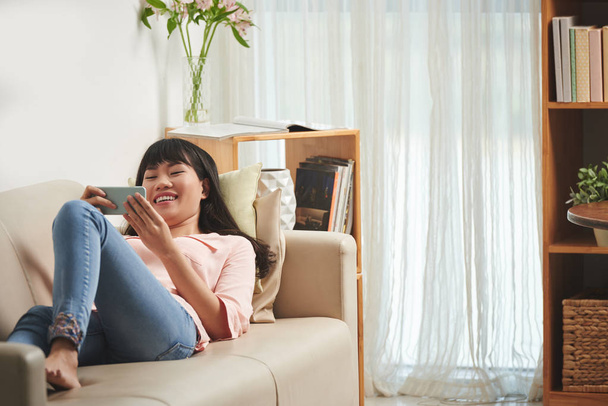woman laughing while laying on sofa - Photo, image