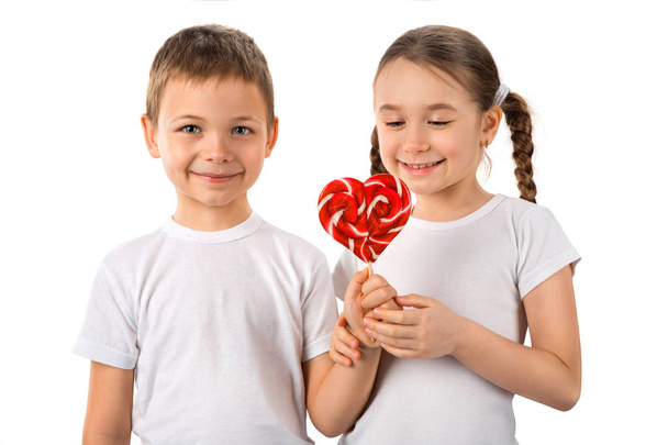 Garçon donne une petite fille bonbons sucette coeur isolé sur blanc. Saint Valentin. Les enfants aiment
. - Photo, image