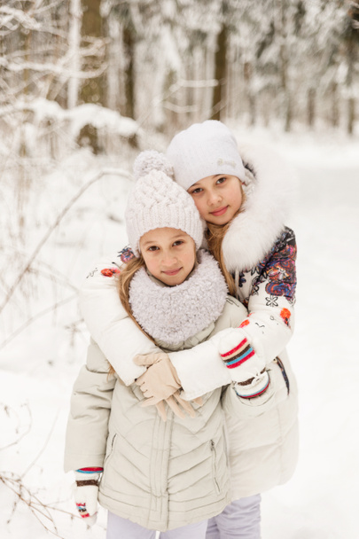 Дві подружки грають у зимовому лісі
.  - Фото, зображення
