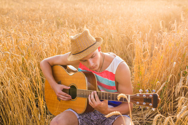 Feliz homem bonito está tocando guitarra no campo
 - Foto, Imagem