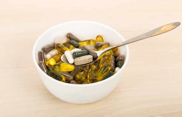 voedingssupplement capsules en tabletten in kom met lepel - Foto, afbeelding