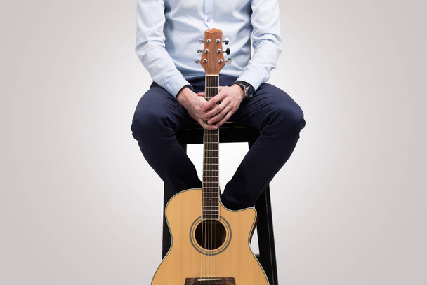 Чоловік тримає гітару в його руках ізольовані на тлі сірого - Фото, зображення