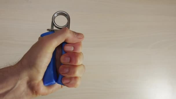 Man squeezes hand grip, strengthens muscles in hand, fingers, wrist, arm. - Πλάνα, βίντεο