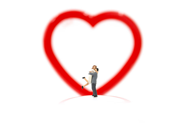 Miniatűr pár átölelve és piros szív fehér háttér - Fotó, kép