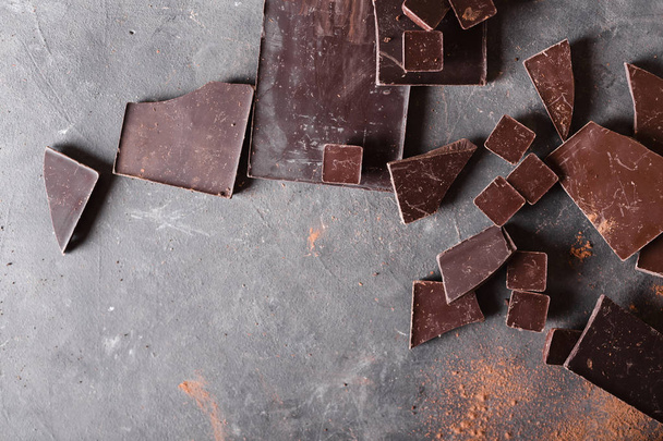 Trozos de chocolate y cacao en polvo. Piezas de chocolate. Una gran barra de chocolate sobre fondo abstracto gris. Fondo con chocolate
.  - Foto, Imagen