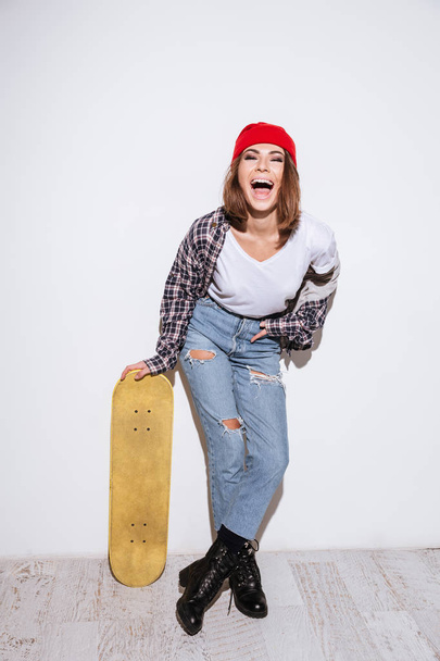 Young lady over white background holding skateboard - 写真・画像