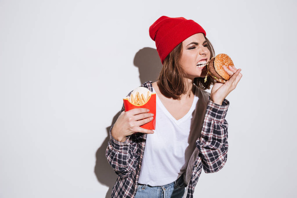Woman holding fries and burger - Fotó, kép