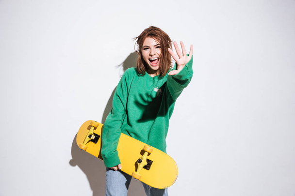 Smiling skater lady with skateboard. - Фото, изображение