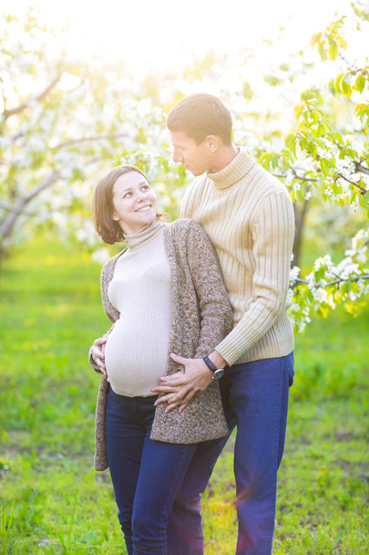 Happy pregnant couple in the blossom garden - Foto, Imagem