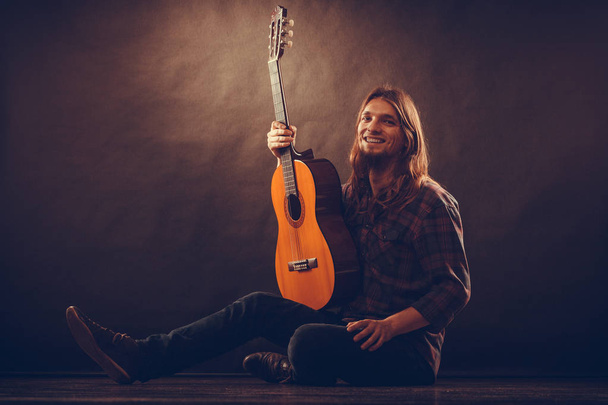 Happy young man with wooden guitar. - Фото, изображение