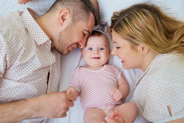 Happy family. Parents with baby on the bed. Closeup - Foto, imagen